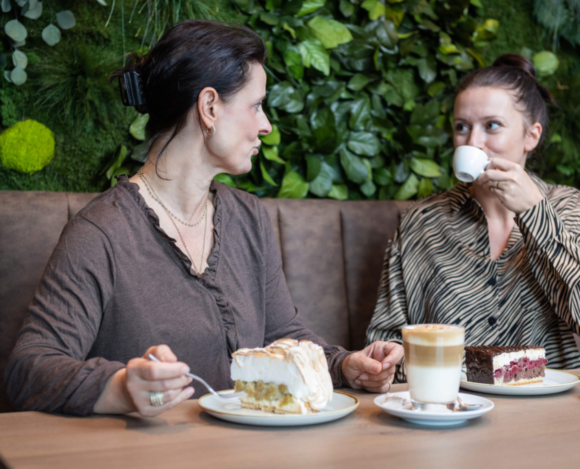 Eine Gruppe von Frauen sitzt an einem Tisch mit Kuchen und Kaffee.